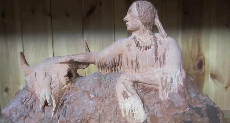 catlinite (pipestone) carving of a warrior reaching out to a bison skull.