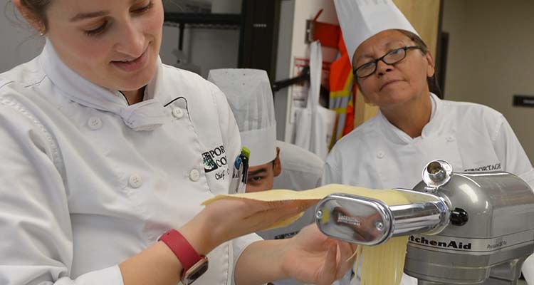 Red Seal Chef and two students watching her make noodles